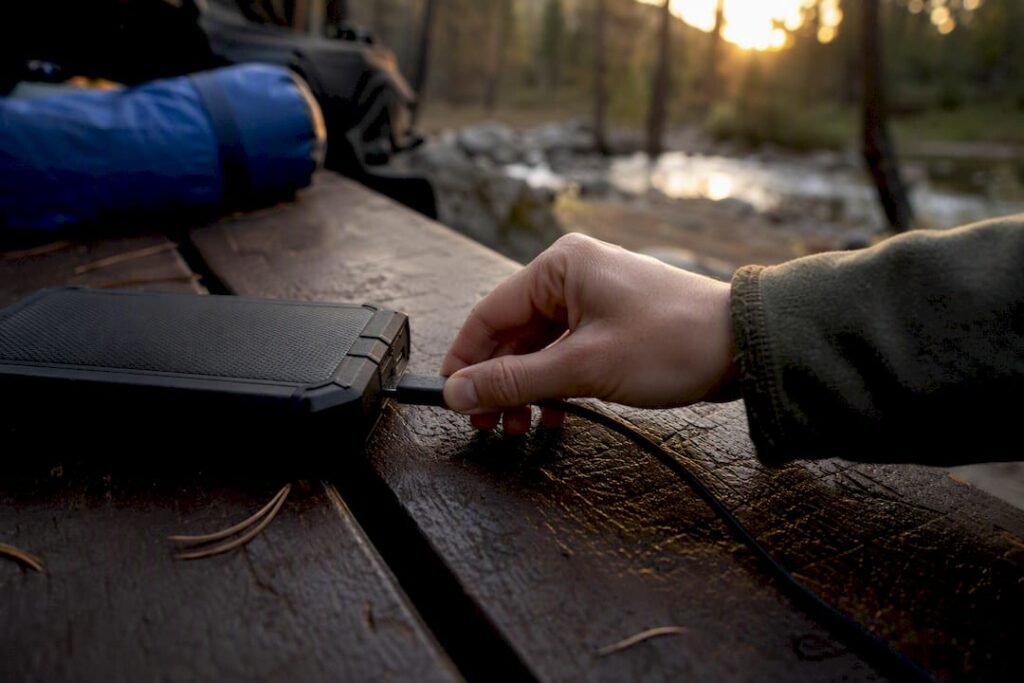 Hand plugging USB-C cable into power bank outdoors
