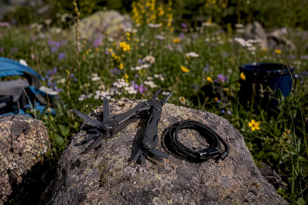 Multi-tool and USB-C cable on wood outdoors
