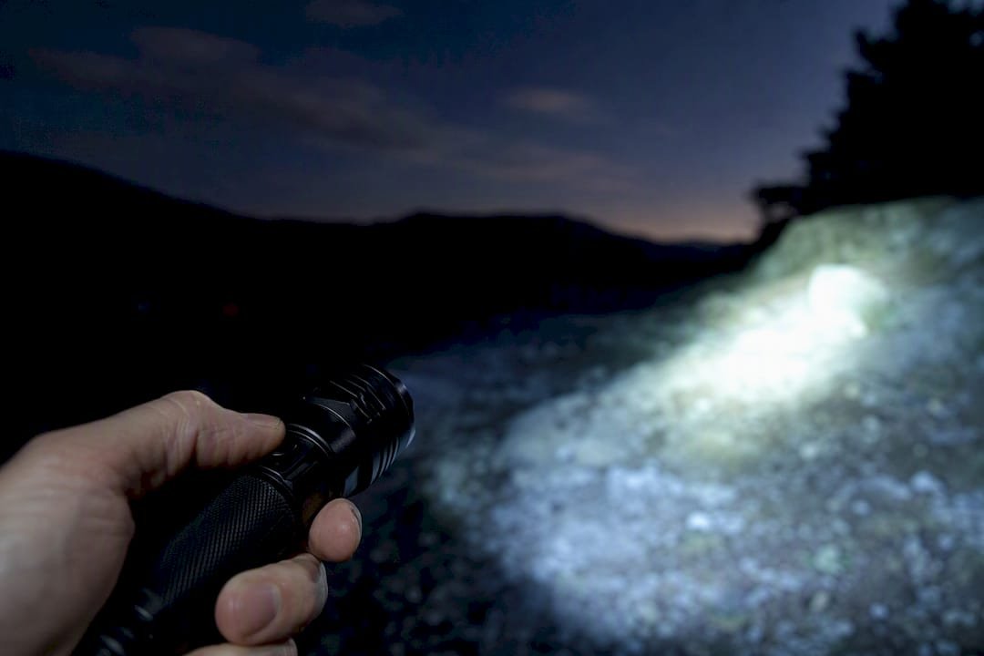 Hand switching flashlight modes outdoors at night