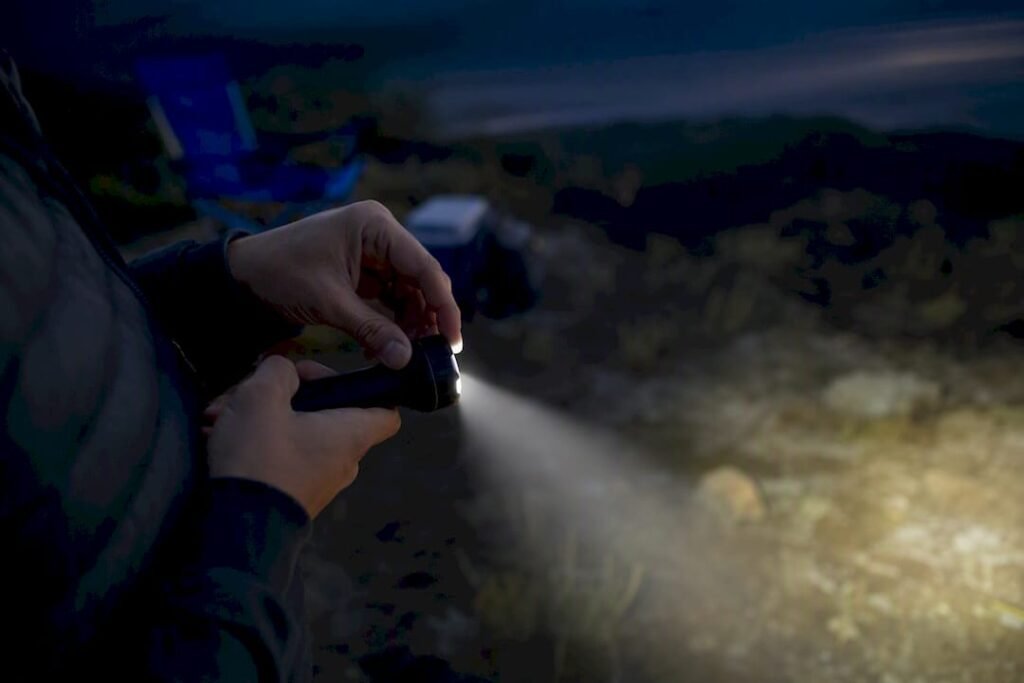 Hand adjusting flashlight beam outdoors at dusk