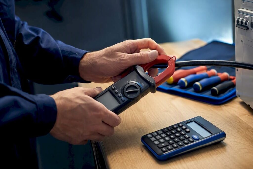 Electrician measuring current with clamp meter